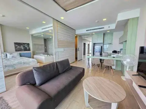 1 Bedroom Condo for Rent at Cetus Beachfront open-plan living area with sofa, dining table and glass-walled bedroom