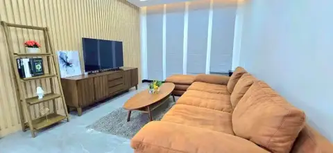 3 Bedroom House for Rent in Chak Nok cozy lounge with sectional sofa and wood-paneled accent wall