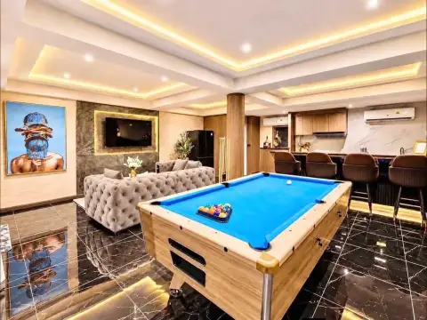 4 Bedroom House for Rent in Chak Nok lounge area with beige sofa, coffee table, and mirrored pool table reflection