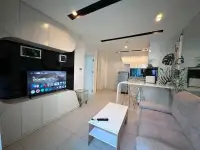 1 Bedroom Condo for Sale at City Center Residence living room with wall-mounted TV, white cabinetry, and kitchen view