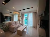 1 Bedroom Condo for Sale at City Center Residence lounge area with sofa, TV and balcony overlooking pool
