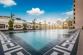 City Garden Tower large outdoor swimming pool with decorative tile border and palm trees under a sunny sky.