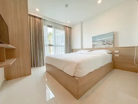 1 Bedroom Condo for Rent at City Garden Tropicana bedroom with wooden bed frame and beach artwork