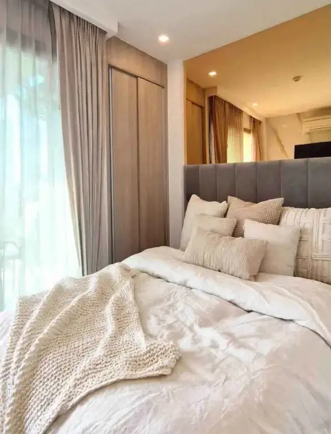 Studio Condo for Sale at City Garden Tropicana cozy bed with cushions near wardrobe and sheer curtains