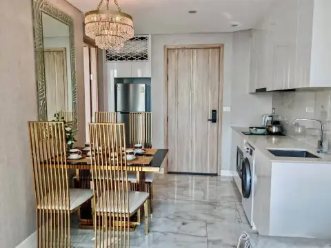 1 Bedroom Condo for Rent at Copacabana Beach Jomtien open-plan dining area with gold chairs, fridge and kitchenette near entrance door