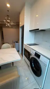 1 Bedroom Condo for Rent at Copacabana Beach Jomtien kitchenette with induction stove, built-in oven, and washing machine beside dining table