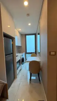 1 Bedroom Condo for Rent at Copacabana Beach Jomtien narrow kitchen with fridge, washer, dining table and city view window