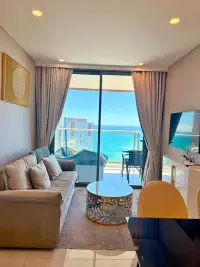 1 Bedroom Condo for Rent at Copacabana Beach Jomtien living room with gray sofa and panoramic sea view balcony