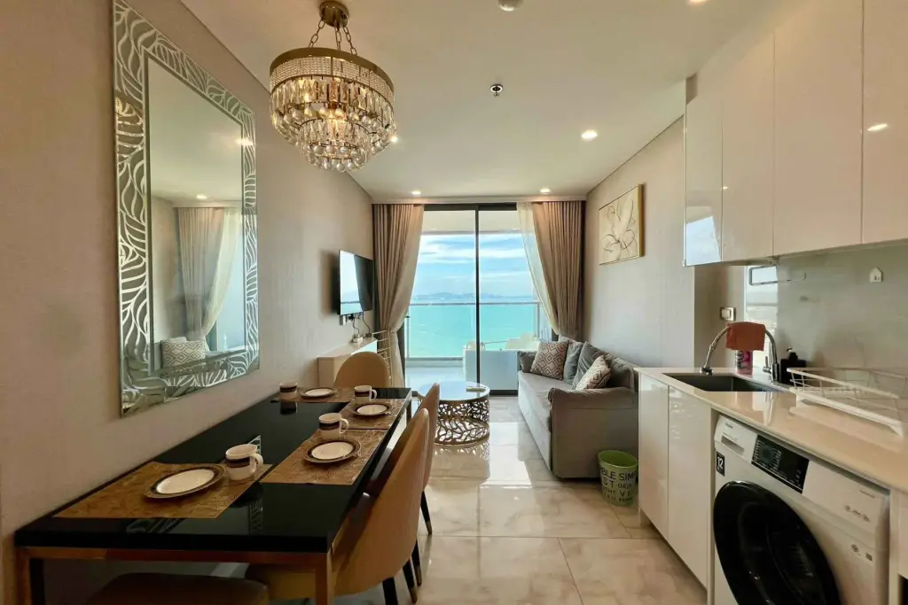 1 Bedroom Condo for Rent at Copacabana Beach Jomtien living area with dining table, sofa and sea-view balcony