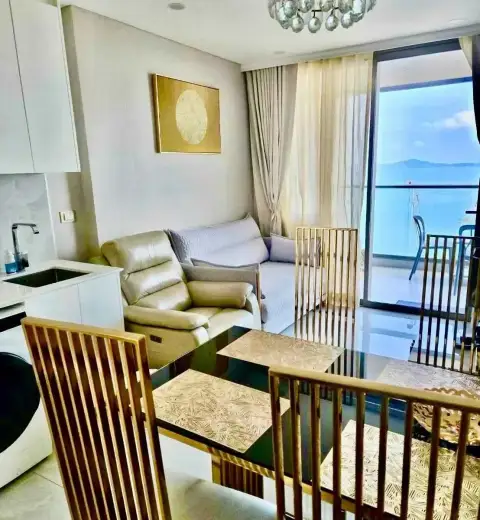 1 Bedroom Condo for Rent at Copacabana Beach Jomtien living and dining area with leather sofa and sea-view balcony