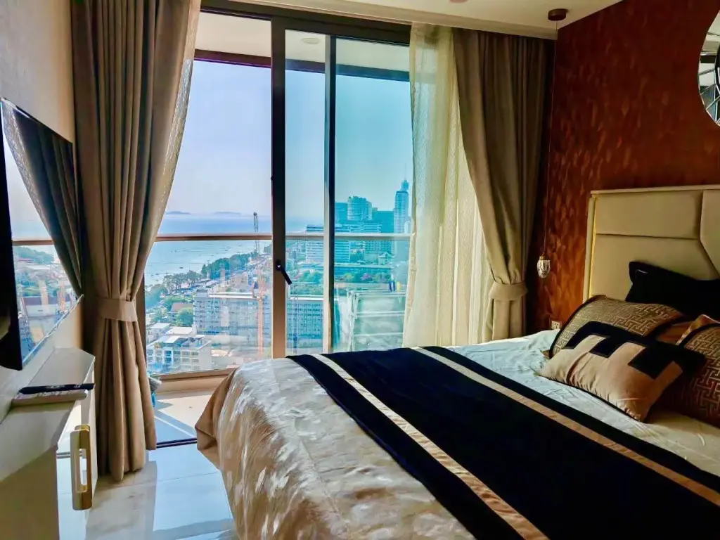 1 Bedroom Condo for Rent at Copacabana Beach Jomtien bedroom with round mirror, upholstered headboard and city view window