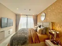 1 Bedroom Condo for Sale at Copacabana Beach Jomtien bedroom with gold accent wall, round mirror, and wall-mounted TV