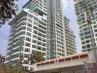 1 Bedroom Condo for Sale at Cosy Beach View high-rise exterior with glass balconies near 7-Eleven storefront