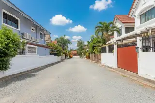 Country Club Villa street view with residential houses, lush hedges, and a clear sky.