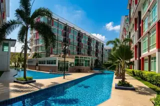 CC Condominium 2 long, narrow swimming pool winding between modern buildings with red accents and palm trees.