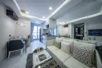 1 Bedroom Condo for Sale at Grand Solaire Noble open-plan living area with white sofa, gold pendant light, and integrated kitchen