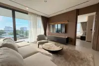 3 Bedroom Condo for Rent at Panora Estuaria bright living room with sectional sofa, round marble coffee table, wall-mounted TV and city view balcony