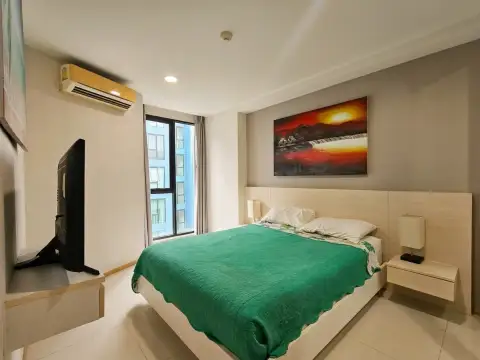 1 Bedroom Condo for Sale at Acqua Condo bedroom with green bedspread, TV, and balcony access