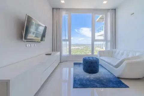 3 Bedroom Condo for Sale at Del Mare cozy lounge with white sofa, blue ottoman, and city view window