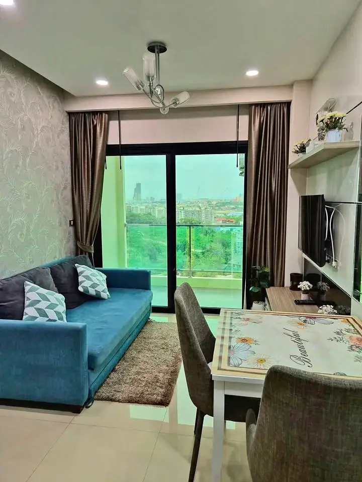 1 Bedroom Condo for Rent at Dusit Grand Condo View living room with blue sofa, dining table, and city balcony view