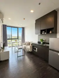 1 Bedroom Condo for Sale at Pattaya Posh open-plan living area with dark wood kitchen and city view window