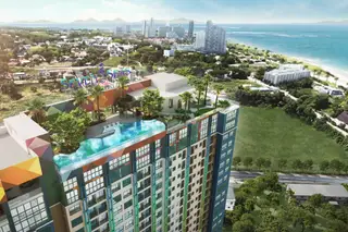 Seven Seas Le Carnival an aerial view of the condo building with a rooftop pool, overlooking Pattaya city and the ocean.
