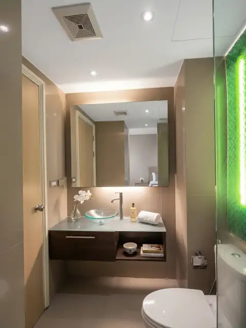 1 Bedroom Condo for Sale at Grande Caribbean bathroom with glass vessel sink, green accent wall, and modern vanity