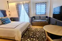 Studio Condo for Sale at Seven Seas Cote d'Azur: Bedroom with bed, striped sofa, round table, and wall-mounted TV.