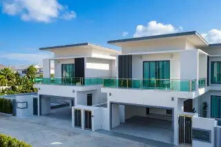 Jin Village modern white houses with flat roofs, balconies, and integrated carports under a blue sky.