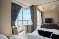 1 Bedroom Condo for Sale at Cetus Beachfront bedroom with white bedding, corner ocean-view windows, and grey curtains
