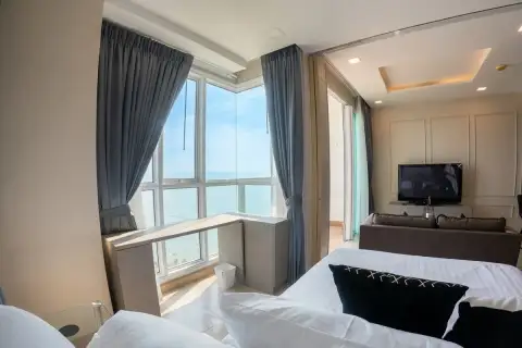 1 Bedroom Condo for Sale at Cetus Beachfront bedroom with white bedding, corner ocean-view windows, and grey curtains