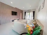 3 Bedroom House for Rent in East Pattaya living room with wall-mounted TV, beige sofa and sliding glass doors