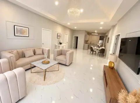 3 Bedroom House for Rent in East Pattaya open-plan living room with beige sofas, chandelier and kitchen view