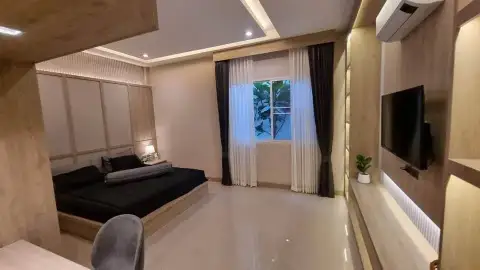 3 Bedroom House for Rent in East Pattaya cozy bedroom with wood paneling, wall-mounted TV and curtained window