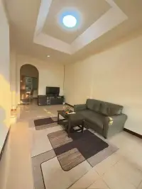 2 Bedroom Townhouse for Rent in East Pattaya living room with leather sofa, TV stand, and patterned area rug