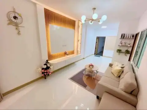 2 Bedroom Townhouse for Sale in East Pattaya living room with wood-paneled TV wall and beige sofa