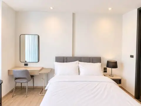 1 Bedroom Condo for Rent at EDGE Central Pattaya bed with white linens, mirror, and bedside lamp