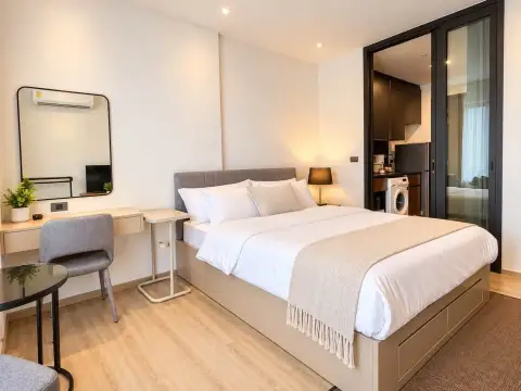 1 Bedroom Condo for Rent at EDGE Central Pattaya bedroom with double bed, desk, and open kitchen area