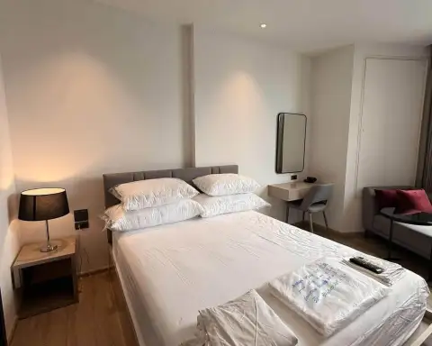 Studio Condo for Rent at EDGE Central Pattaya bed with crisp white linens, nightstand lamp, and mirror