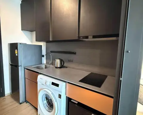 Studio Condo for Rent at EDGE Central Pattaya compact kitchenette with stove, sink, fridge, and washing machine