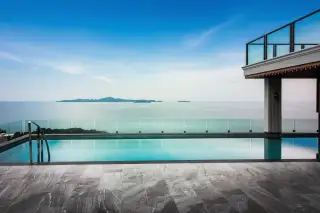 Elysium Residences infinity pool overlooking the ocean and distant islands under a blue sky.
