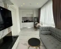 1 Bedroom Condo for Rent at The Empire Tower Pattaya open-plan kitchen with white cabinets and gray sofa seating area