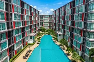 CC Condominium 1 long outdoor swimming pool surrounded by palm trees and modern condo buildings with red accents.