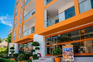 C View Residence Pattaya exterior, an orange and white building with glass entrance, steps, and landscaped garden.