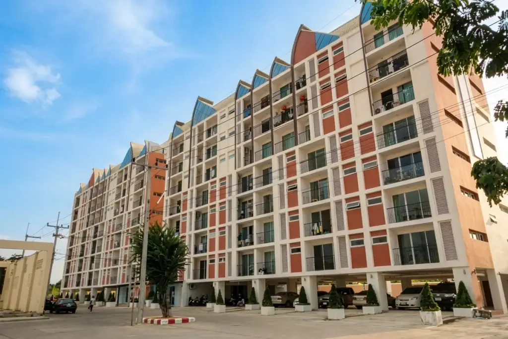 Life Vela Casa condo building exterior with colorful roof accents, seen from a narrow street with lush greenery.