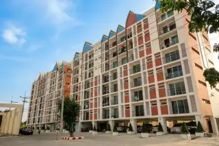 Life Vela Casa condo building exterior with colorful roof accents, seen from a narrow street with lush greenery.