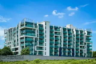 The Feelture Condominium exterior view with a large green swimming pool, palm trees, and modern architecture.