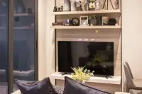 Studio Condo for Sale at Andromeda Condominium living area detail showing flat-screen TV, decorative shelves, and navy blue sofa cushions