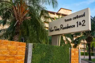View Talay Residence 1&2 entrance sign with Thai script surrounded by lush palm trees in Pattaya