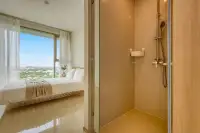 1 Bedroom Condo for Sale at The Riviera Jomtien walk-in shower next to the bedroom with a city view.
